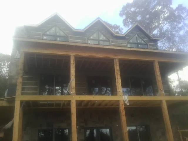 Dormers and porch framing on a large log home under construction — Roof Coating work by our crew in Charleston
